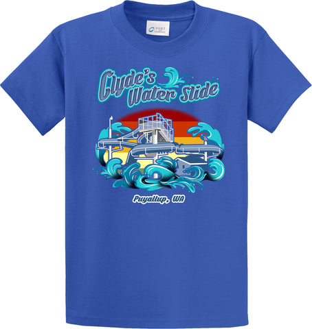 A blue short-sleeved t-shirt with a vibrant graphic on the front. The design features the text "Clyde's Water Slide" in stylized teal lettering with a backdrop of waves and a waterslide structure. There's an orange-red sun setting behind the waterslide. At the bottom of the design, the text "Puyallup, WA" is written in white. The shirt brand is indicated by a label reading "PORT & COMPANY" near the collar.